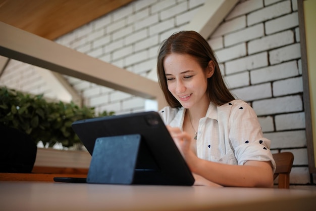 Young attractive woman interacting with the mobile tablet in cafe