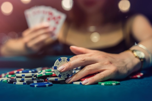 Young attractive woman playing poker at table with stacks of chips and cards