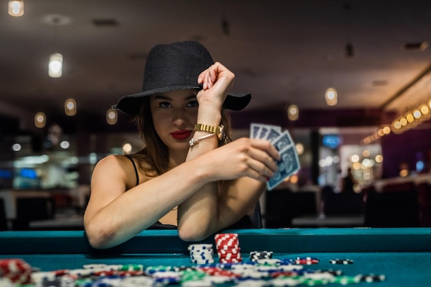 Young attractive woman playing poker at table with stacks of chips and cards