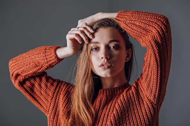 Young attractive woman in a red sweater on a gray background Emotions