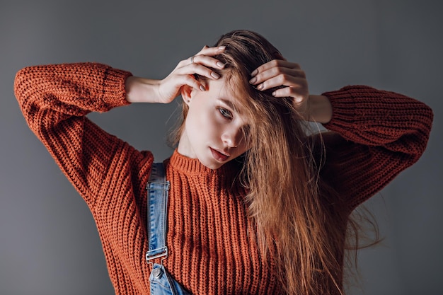 Young attractive woman in a red sweater on a gray background Emotions