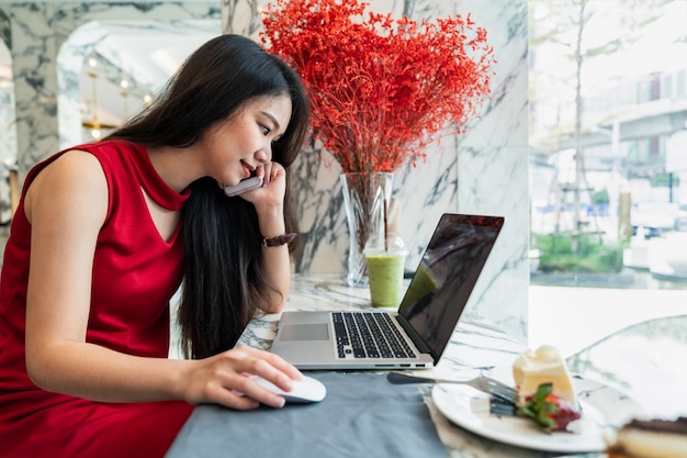 Young attractive woman smiling using smartphone and laptop working and contact in coffee cafe