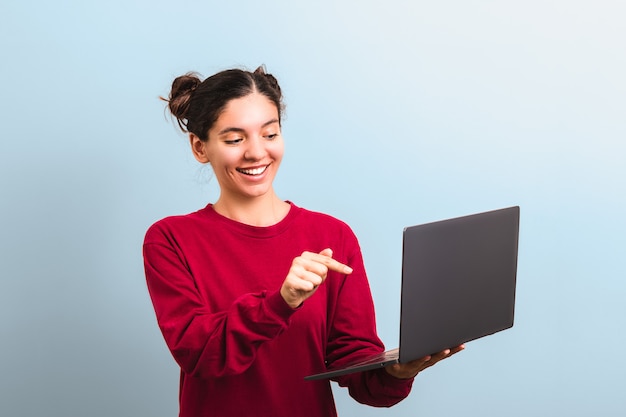 Young attractive woman student with funny face holding a laptop and pointing into it applaying for university or college enrolment