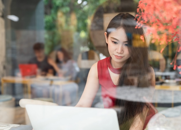 Young attractive woman using laptop in coffee shop - Social connection and lifestyle concept