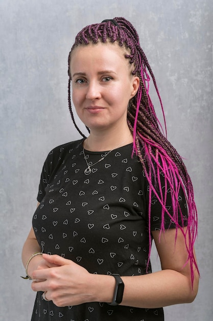 Young attractive woman with pink dreadlocks on gray background Portrait of middleaged woman with dreads Vertical frame