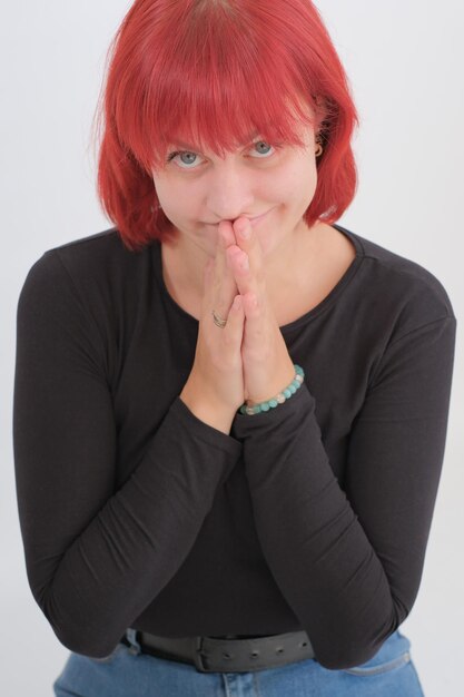 A young attractive woman with a short orange hairstyle in a black Tshirt and jeans posing in the studio on a white background