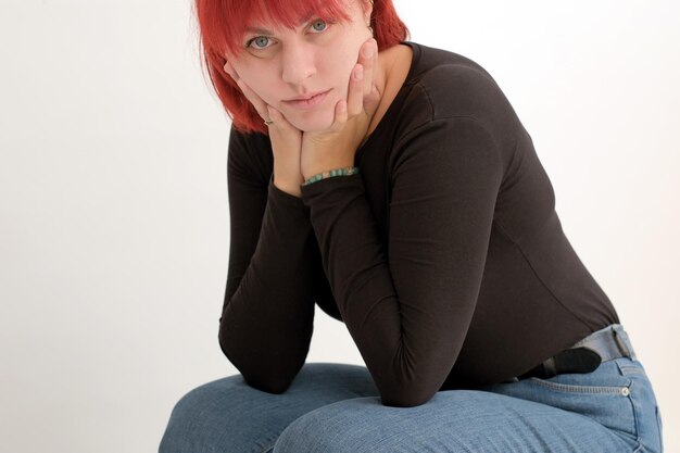 A young attractive woman with a short orange hairstyle in a black Tshirt on a white background