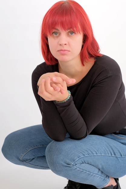 A young attractive woman with a short orange hairstyle in a black Tshirt on a white background