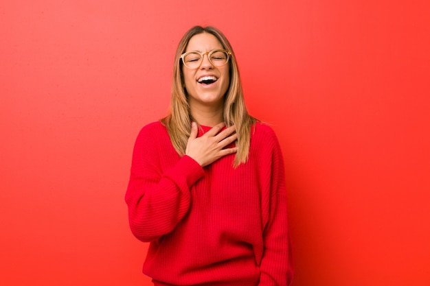 Young authentic charismatic woman laughs out loudly keeping hand on chest