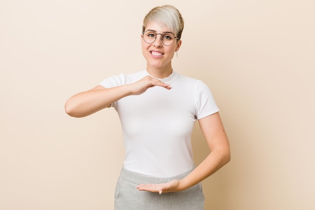 Young authentic natural woman wearing a white shirt holding something with both hands, product presentation.