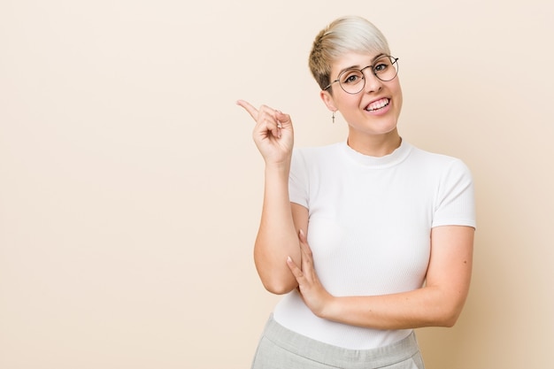 Young authentic natural woman wearing a white shirt smiling cheerfully pointing with forefinger away.