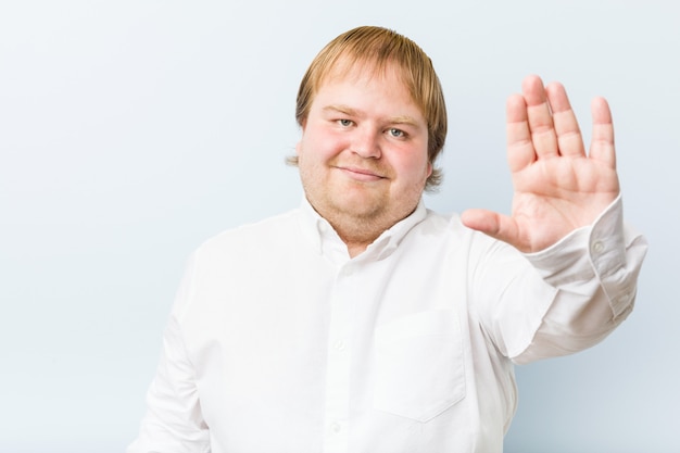 Young authentic redhead fat man standing with outstretched hand showing stop sign, preventing you.