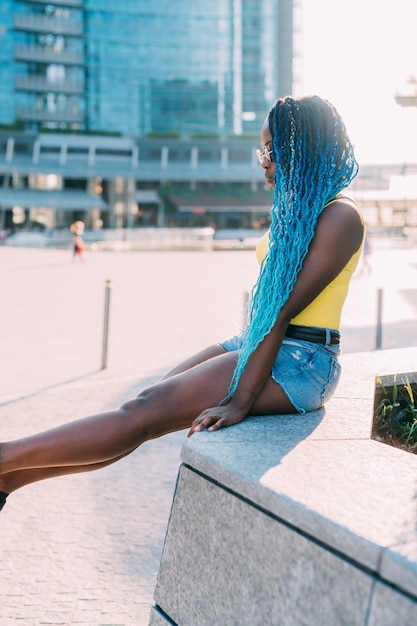 Young back millennial woman sitting outdoor back light looking away