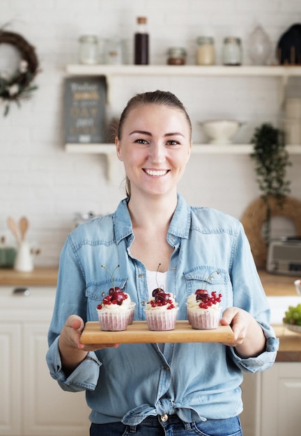 Young baker woman holding cupcakes Happy smiling and cheerful