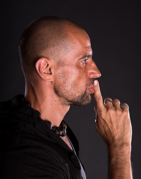 Young bald handsome man showing silence gesture