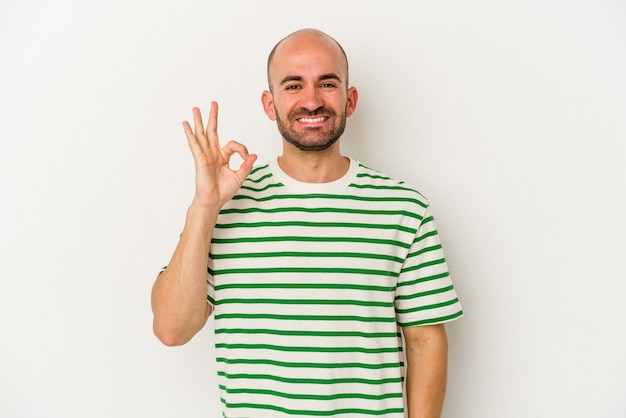 Young bald man isolated on white background cheerful and confident showing ok gesture.