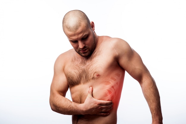 Young bald man sportive physique holds on sore rib