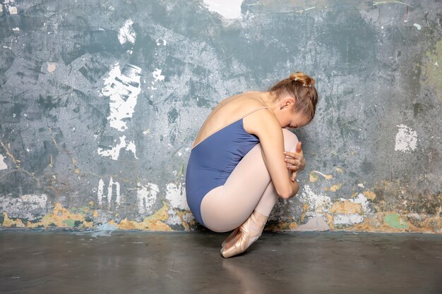 Photo young ballerina in the pose by the grungy wall