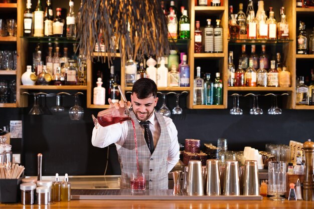 Young bartender making cocktails for his clients to enjoy very tasty drinks Concept consumption alcohol bartender