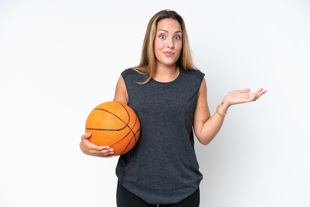 Young basketball caucasian player woman isolated on white background having doubts while raising hands