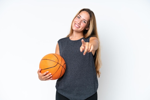 Young basketball caucasian player woman isolated on white background pointing front with happy expression