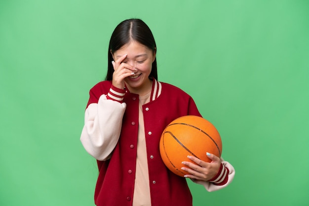 Young basketball player asian woman over isolated background laughing