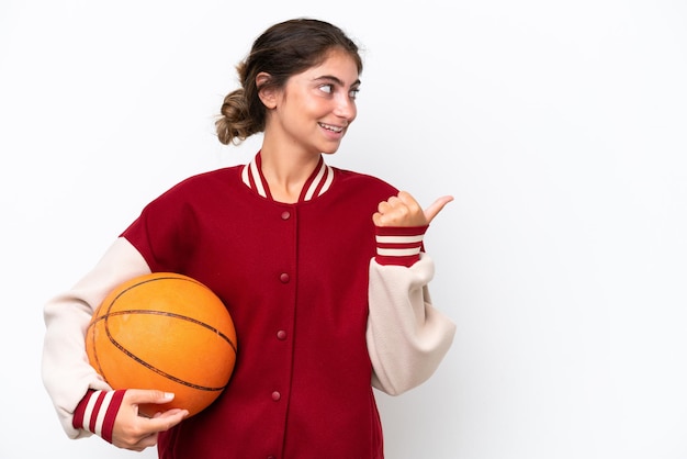 Young basketball player woman isolated on white background pointing to the side to present a product