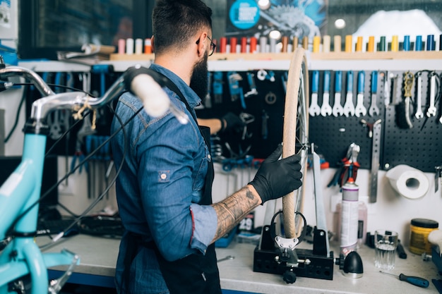 Young beard bicycle mechanic repairing bicycles in a workshop.