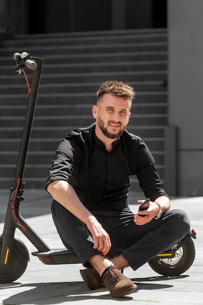 Young beard man on electric scooter with smartphone in hand