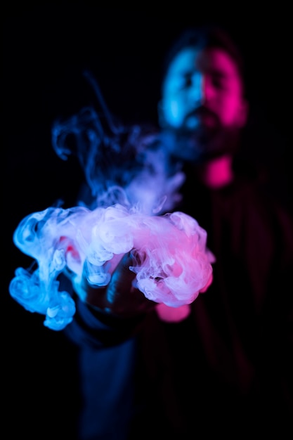 Young bearded arab man smoking vape and doing tricks with colored lights.