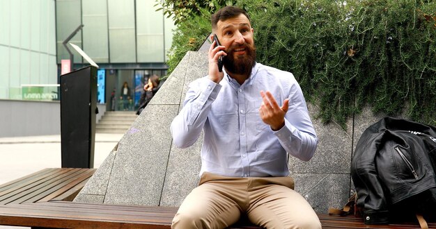 Young bearded businessman talking on his phone outdoors.