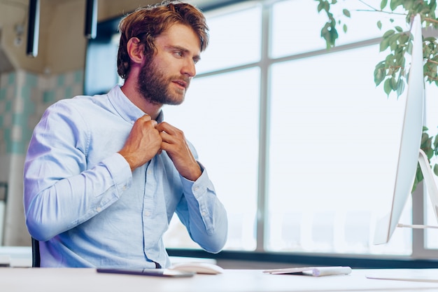 Young bearded businessman using his computer in a modern office place. Business concept