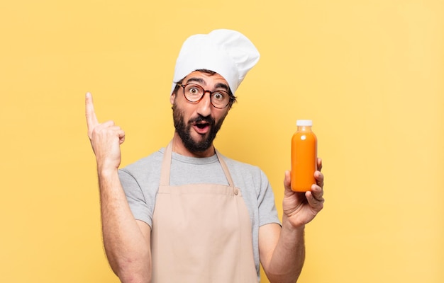 Young bearded chef man celebrating successful a victory and holding a smoomthy