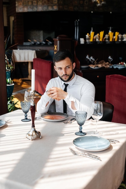 A young bearded male businessman is sitting at a table in a fine restaurant and waiting for his order Customer service in the catering