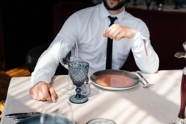 A young bearded male businessman is sitting at a table in a fine restaurant and waiting for his order Customer service in the catering