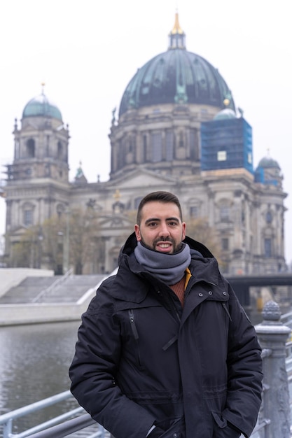 Young bearded male tourist happily having his picture taken with the Berlin Cathedral in the background