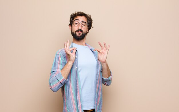 Young bearded man against flat wall