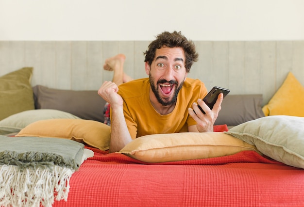 Young bearded man on a bed with his mobile phone