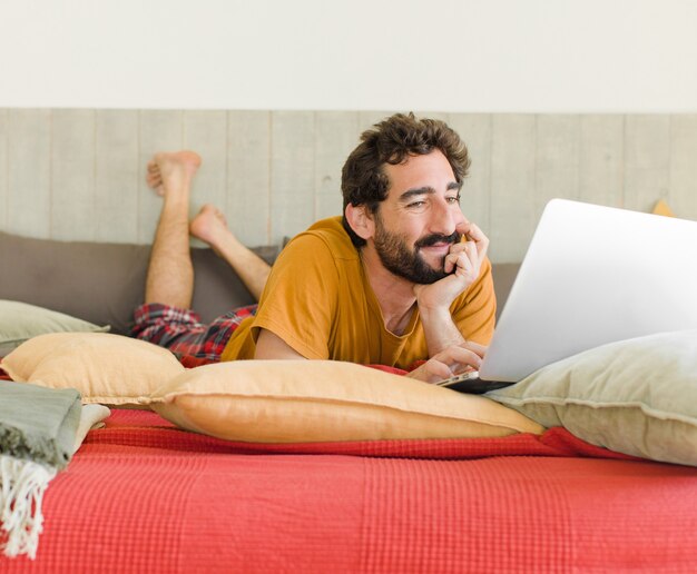 Young bearded man on a bed with a laptop