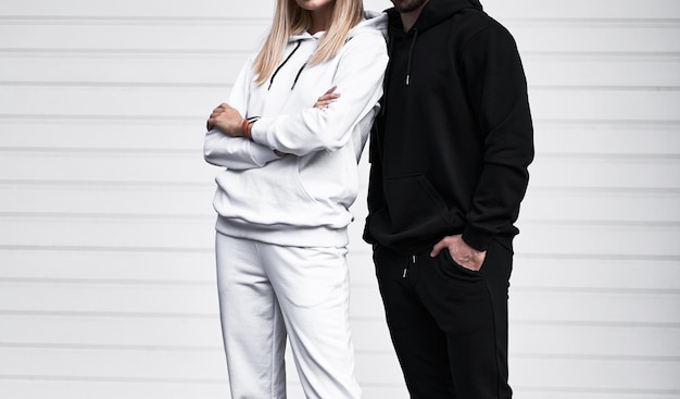 Young bearded man and blonde girl is standing in plain hoodie for logo printing Clothing mockup for hoodie Autumn youngsters streetwear