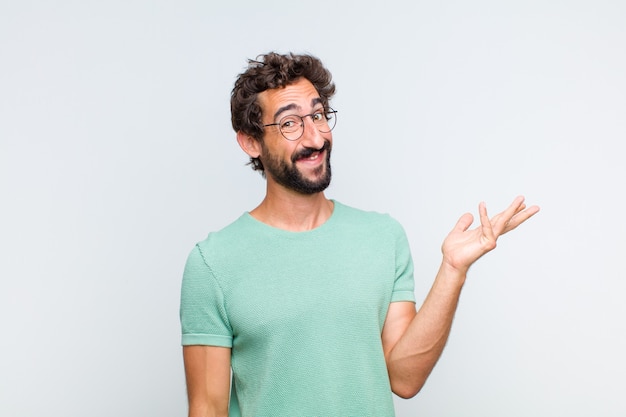 Young bearded man feeling happy, surprised and cheerful, smiling with positive attitude, realizing a solution or idea