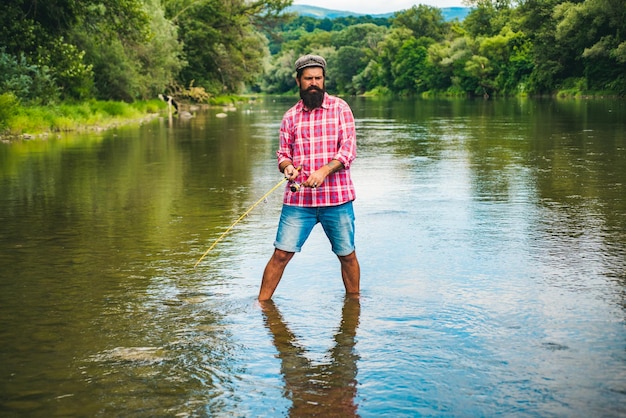 Young bearded man fishing at a lake or river flyfishing