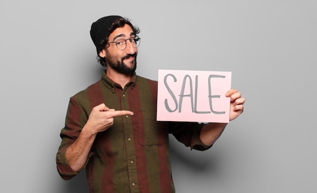 Young bearded man holding SALE signboard. sale concept