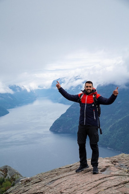 Young bearded man raising his hands with Lysefjord fjord in the background concept of success and selfimprovement