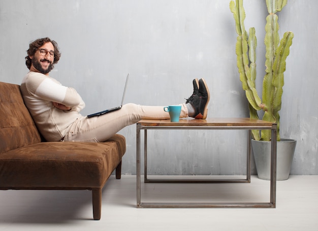 Young bearded man sitting on a leather sofa in a vintage living room