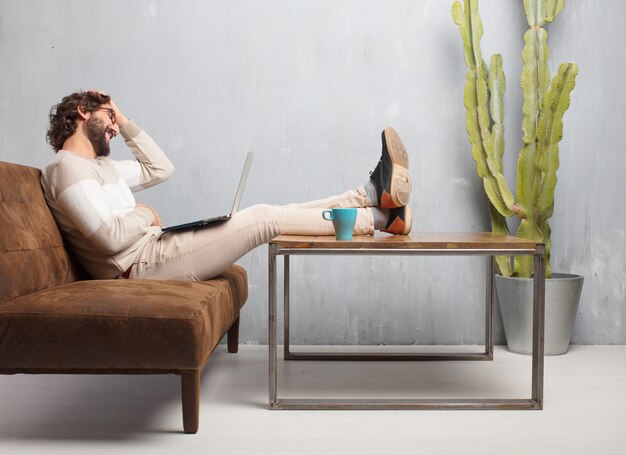 Young bearded man sitting on a leather sofa in a vintage living room