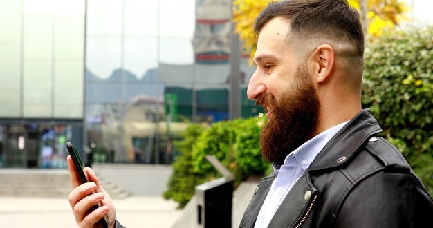 Young Bearded man smiling happy doing video call using smartphone at city.