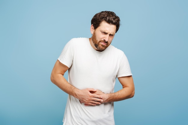 Young bearded man with health problems stomachache posing in studio