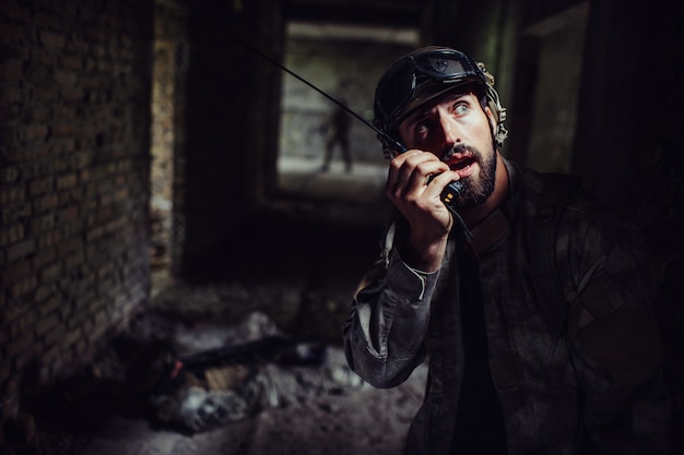 Young and bearded warrior is talking to portable radio.