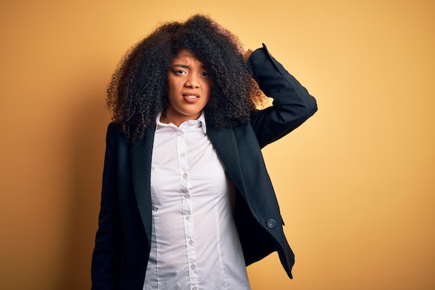 Young beautiful african american business woman with afro hair wearing elegant jacket confuse and wonder about question Uncertain with doubt thinking with hand on head Pensive concept